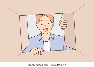 Man looks into cardboard box and looks inside with curiosity receiving order from courier from online store delivery service. Curious guy with smile inspects contents of box after moving