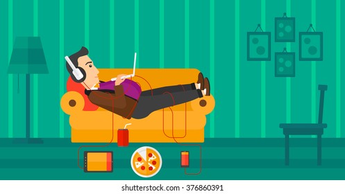 Man lying on sofa with many gadgets.
