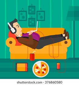 Man lying on sofa with many gadgets.