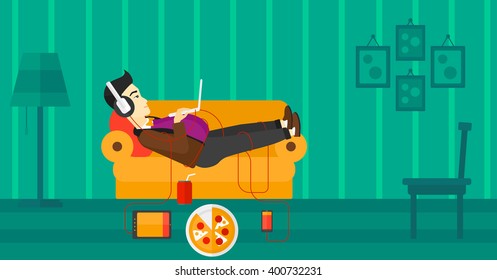Man lying on sofa with many gadgets.