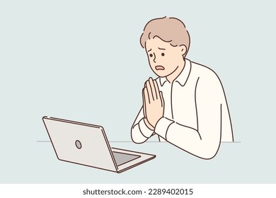 Man manager prays sitting at table with laptop asking god for help after making mistakes in project. Guy office worker prays talking with partner on video link forgiveness for breach of agreements