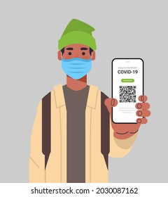man in mask holding digital immunity passport with qr code on smartphone screen risk free covid-19 pandemic
