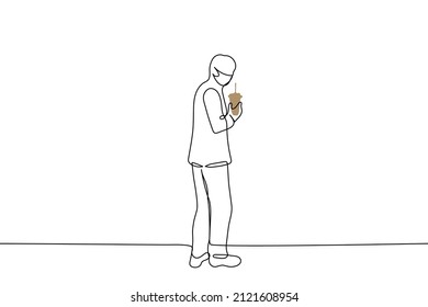  man in a mask stands facing the viewer and holds a cup of coffee - one line drawing vector. coffee to go concept 