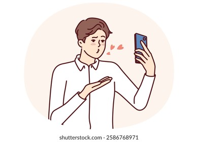 Man with mobile phone sends air kiss to interlocutor during video call to girlfriend who has left on business trip. Guy with smartphone records video of valentine wishing to kiss bride from distance