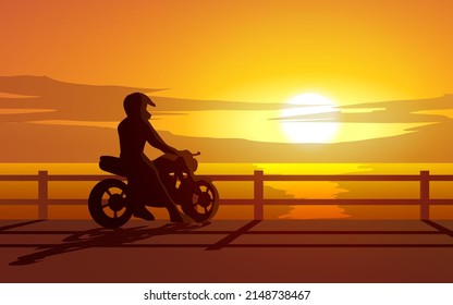 Man with motorcycle looking at sunset at beach