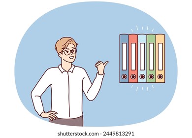 Man Office Worker zeigt mit dem Finger auf mehrfarbige Ordner für Dokumente. Der Typ in Business-Kleidung gibt Ratschläge zum Auffinden von Berichten oder empfiehlt ein System zum Aufbewahren von Finanzpapieren
