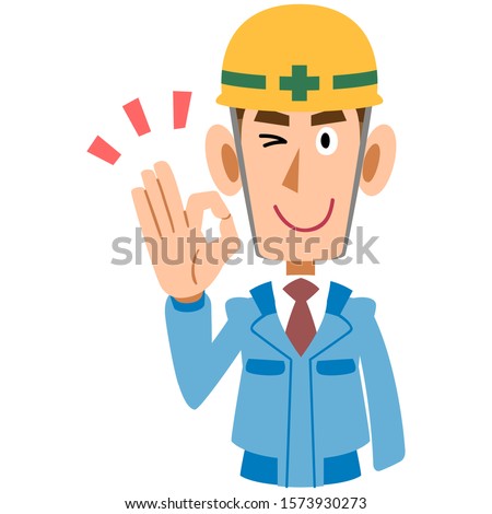 A man on the construction site in blue work wear shows an OK hand sign