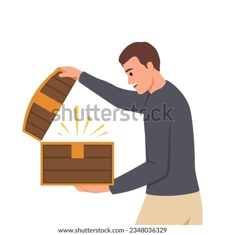 Man with open chest filled with treasures or jewels for concept of lucky find and luck. Delighted guy holds wooden chest with rays of light illuminating face
