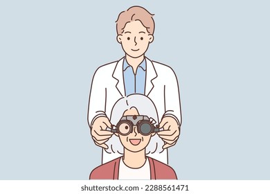 Man optometrist putting on ophthalmic glasses on gray-haired elderly female patient during vision treatment. Old woman smiling at ophthalmologist appointment and rejoicing at improvement in vision 