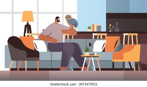 man with owl guy taking care of pet animal bird living room interior horizontal