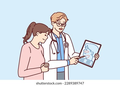 Man plastic surgeon consults woman patient demonstrating tablet with ways to tighten skin on face to get rid of wrinkles. Girl turned to plastic surgeon for help to do facial surgery 