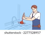 Man plumber uses plunger to clear blockage in sink in kitchen or bathroom. Guy working as plumber is dressed in overalls and is engaged in elimination breakdown associated with debris stuck in pipe 