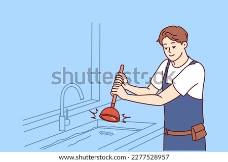 Man plumber uses plunger to clear blockage in sink in kitchen or bathroom. Guy working as plumber is dressed in overalls and is engaged in elimination breakdown associated with debris stuck in pipe 