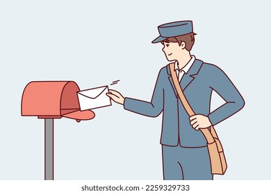Man in postman uniform throws paper letter into metal mailbox located on street. Guy delivers fresh mail with alerts from government agencies or messages from friends