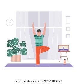 Man practicing yoga at home living room and watching online classes on laptop. Male in Tree pose doing fitness exercises with online tutorials. Life balance, healthy lifestyle and well being concept.