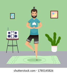 Man Practicing Yoga At Home. Meditation Pose, Young Guy With Ponytail Meditate Standing At One Leg At Carpet. Keep Calm. Music Center, Houseplant, Pictures At Wall. Qurantine Isolation. Stay At Home