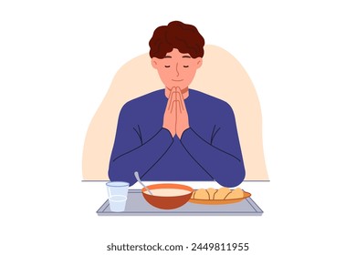 Man prays sitting at table with food, observing christian tradition and expressing gratitude to god. Guy prays with eyes closed and palms folded in front of chest, rejoicing at having money for food