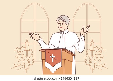 Man priest with smile leads sermon in catholic church, standing behind podium with crucifix, dressed in white robe. Gray-haired priest, rector of temple, encourages visitors to pray get to heaven