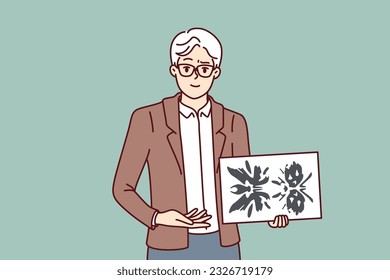 Man psychotherapist holds picture of rorschach test to determine patient personality type. Elderly psychotherapist demonstrates piece of paper with blots for medical psychiatric experiment.