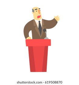 A man public speaking behind a red tribune in a brown suit