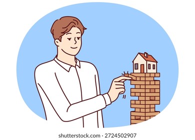 El hombre pone la casa en peligro al tirar de bloques de debajo de la construcción por concepto de préstamo hipotecario de riesgo o prenda de bienes raíces. La casa necesita un seguro y el reembolso de la hipoteca del banco de crédito