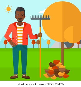 Man with rake near tree and heap of leaves.