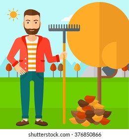 Man with rake standing near tree and heap of autumn leaves.