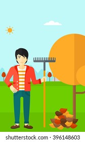 Man with rake standing near tree and heap of autumn leaves.