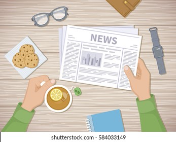 Man reading the latest news at breakfast. Human hands holding tea with lemon and newspaper, cookies, glasses, smart watch, notebook, purse. A good start of the day before working. View from above.