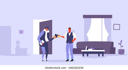 man receiving wrapped gift box from male courier express delivery concept modern living room interior flat horizontal full length
