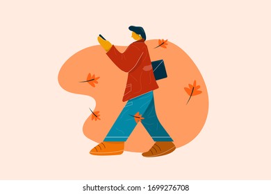 Man in red coat and blue trousers or jeans walking and listening to music with his mobile phone.