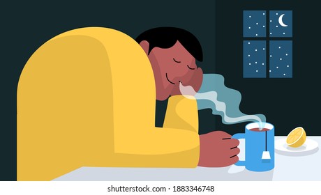 Man relaxing and dreaming while smelling tea aroma. Drinking tea during winter time in the kitchen at home with window and moon in the background. Tea time and relax concept.