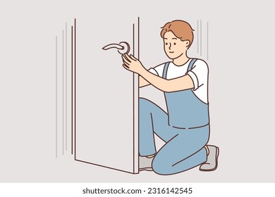 Man repairs door by changing lock to prevent criminals from entering apartment. Guy repairman in overalls restores door or repairs doorknob for advertising professional repair service