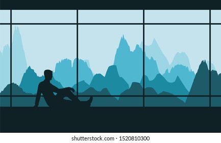 Man resting by the window with a view of the mountains. Silhouette of relaxed young man lying on the floor and dreaming at his future.