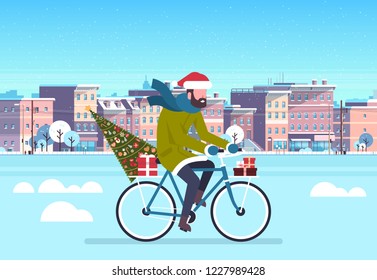 Man riding bike with fir tree gift box by city street buildings cityscape background merry Christmas new year concept flat horizontal vector illustration