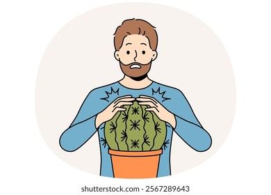 Man is scared and touches cactus and gets wound for concept of problems associated with unshaven hair and need for depilation. Funny stupid guy pricked himself touching cactus in pot