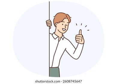 Man in shirt smiles and gives thumbs up to show approval of proposed plan to achieve business goals. Happy guy showing thumbs up peeking around corner sign of successful result of work done