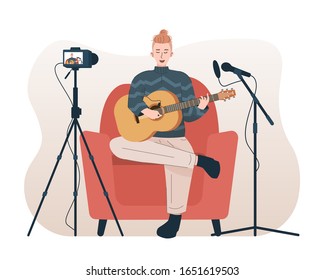 Man singing and playing acoustic guitar while recording video using camera and microphone. Male singer doing cover song for his online video channel