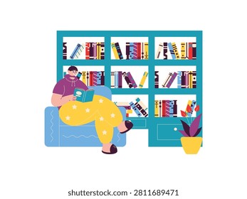 Man sits in armchair reading book in front of bookcase, next to plant with flowers.