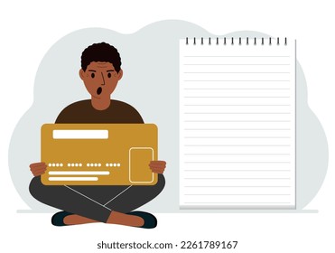 A man sits cross-legged in his hands holding a large credit card next to a close-up notepad for text. Concept of credit card, expense planning, income planning.