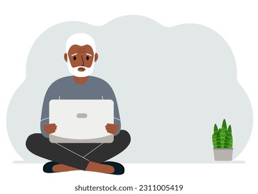 A man sits cross-legged in his hands holding a laptop. The concept of work, education, reading, watching videos.