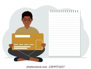 A man sits cross-legged in his hands holding a large credit card next to a close-up notepad for text. Concept of credit card, expense planning, income planning.