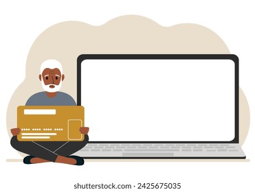 A man sits cross-legged and holds a large plastic card. Next to the man is a large laptop with space for text.