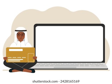 A man sits cross-legged and holds a large plastic card. Next to the man is a large laptop with space for text.
