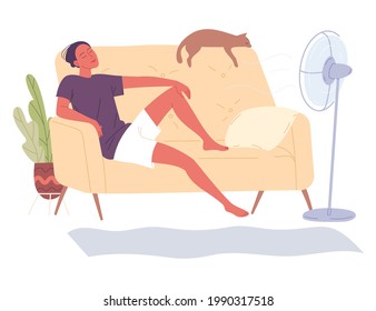 Man sits at home on the couch by the fan and enjoys the freshness of a hot day.