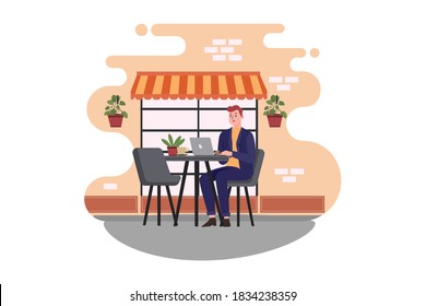 A man sitting at a cafe working on a laptop