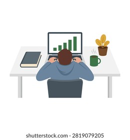 Man sitting at desk working on laptop with graph on screen, mug and plant nearby