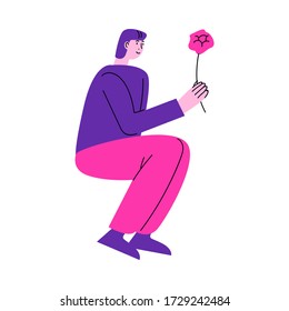 Man sitting and giving pink flower to his girlfriend during date