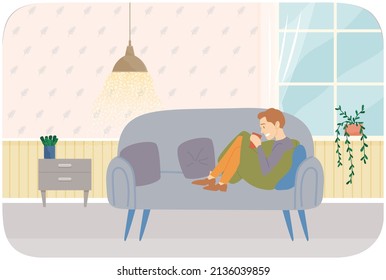 Man sitting on couch drinking coffee or tea. Person spends time at home alone. Guy resting with drink on comfortable sofa in living room. Male character in apartment during day off, weekend