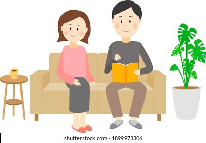 A man sitting on the couch reading a book and a woman sitting